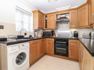 A kitchen with wooden cabinets and appliances at 5 Styleman Road in Hunstanton