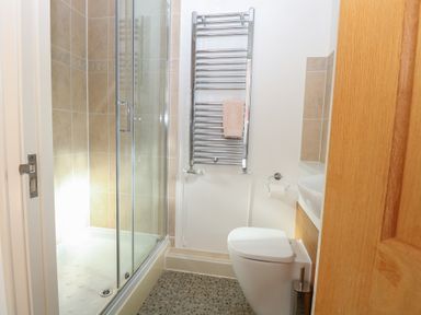 A bathroom with a shower, toilet, towel warmer, and sink at 5 Styleman Road, Hunstanton
