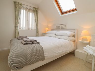 A bedroom with a double bed folded towels bedside tables with lamps and a skylight window at Y Bwthyn Newport in Newport Pembrokeshire