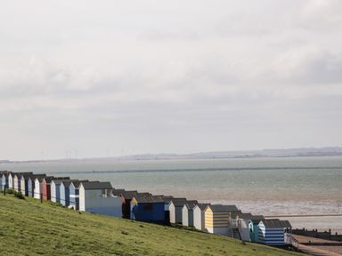 A row of colorful beach huts on a grassy slope by the sea at 4 Country View Park in Graveney near Seasalter