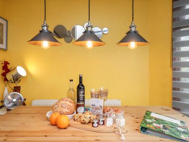 A kitchen table with food items and drinks under three hanging lights at 4 Country View Park in Graveney near Seasalter