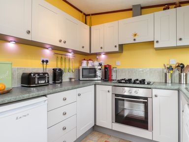 A kitchen with white cabinets a microwave a stove and various utensils at 4 Country View Park in Graveney near Seasalter