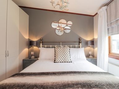 A bedroom with a bed cushions bedside tables lamps and a wardrobe at 4 Country View Park in Graveney near Seasalter