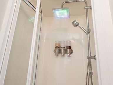 A shower area with a rain showerhead dispensing water and three wall-mounted dispensers in a bathroom at 4 Country View Park in Graveney near Seasalter