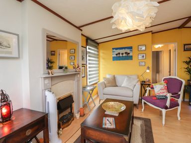 A living room with a fireplace beige sofa purple armchair and dark wooden coffee table at 4 Country View Park in Graveney near Seasalter