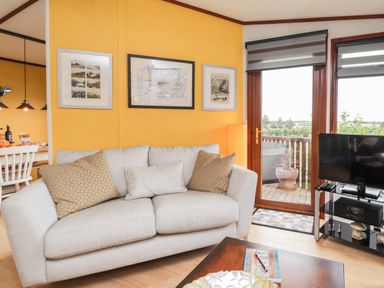 A living room with a gray sofa and pictures on the yellow wall at 4 Country View Park in Graveney near Seasalter