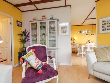 A living room with a purple armchair and decorative cabinet next to a dining area at 4 Country View Park Graveney near Seasalter