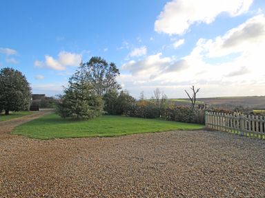 An outdoor area with a gravel driveway green lawn trees and a wooden fence at Valley View in Mevagissey