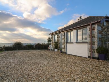 A stone and brick house with gravel ground and a small white table and chairs outside at Valley View in Mevagissey