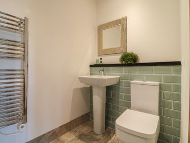 A bathroom with a sink toilet mirror and towel rack at Valley View in Mevagissey