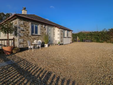 A stone and white exterior house with a gravel driveway and a small white table and chairs outside at Valley View in Mevagissey