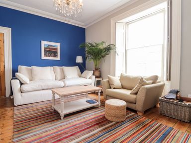A living room with sofas a coffee table a striped rug and a plant at The Water House in Falmouth