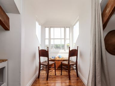 A narrow seating area with two wooden chairs and a chest by a window at The Water House in Falmouth