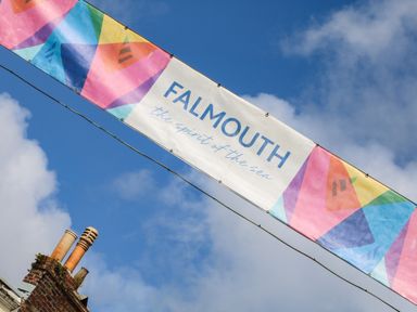 A colorful banner with the text Falmouth the spirit of the sea above a rooftop with chimneys against a blue sky at The Water House in Falmouth