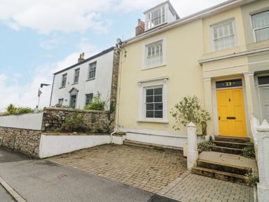 A row of attached houses with stone and brick walls and a yellow door numbered 23 at The Water House in Falmouth
