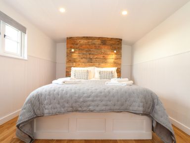 A bedroom with a large bed wooden headboard and two folded towels on the bed at Sebright in St Austell
