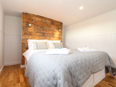 A bedroom with a bed featuring a wooden headboard pillows and towels on the bed at Sebright in St Austell