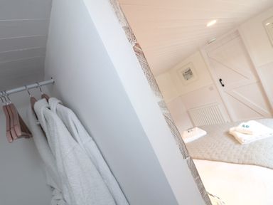 A bedroom with a bed and towels on it and robes hanging on a rail at Sebright in St Austell