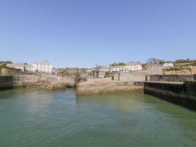 A harbor with stone walls and buildings along the waterfront at Sebright in St Austell