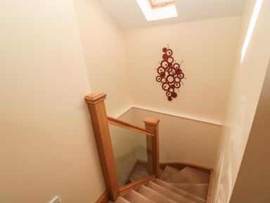 A staircase with wooden railing and glass panels under a skylight at Stable D'or in Embleton