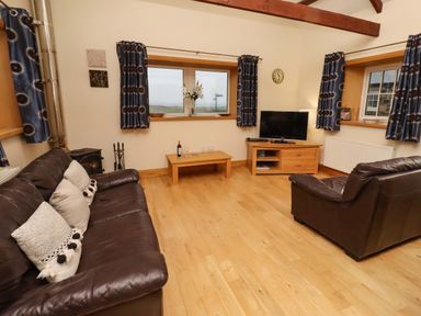 A living room with sofa and television at Stable D'or in Embleton