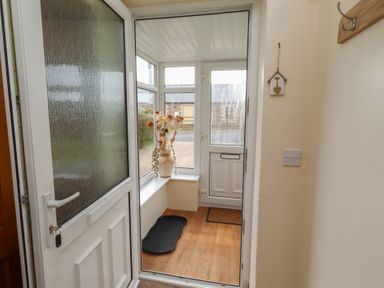 A conservatory with a door, window, and a vase at The Retreat in Embleton
