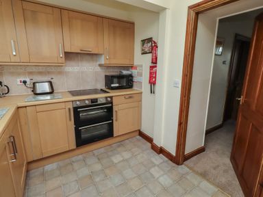 A kitchen with cabinets, stove, microwave and kettle at The Retreat in Embleton