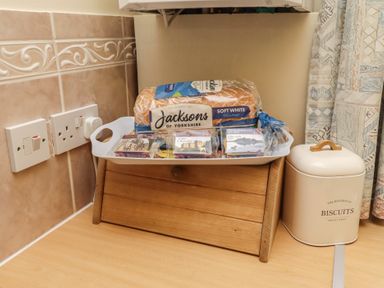 A wooden tray with bread and treats in a kitchen at The Retreat in Embleton