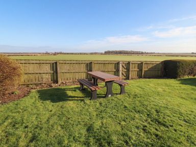 A garden with a picnic table and grass at The Retreat in Embleton