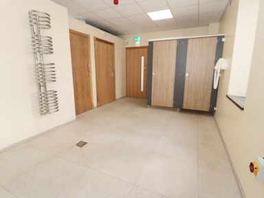 A tiled room with wooden doors metal radiator stalls and a wall-mounted hairdryer at Low Croft in Embleton