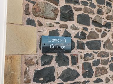 A stone wall with a sign reading Lowcroft Cottage at Low Croft in Embleton