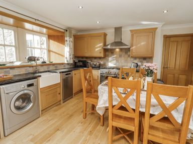 A kitchen with wooden dining table and appliances at Low Croft in Embleton