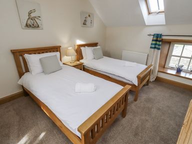 A bedroom with two single beds and a window at Low Croft in Embleton