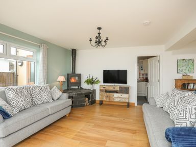 A living room with two sofas a wood burning stove and a television on a cabinet at Red Ridge in Llandanwg near Harlech