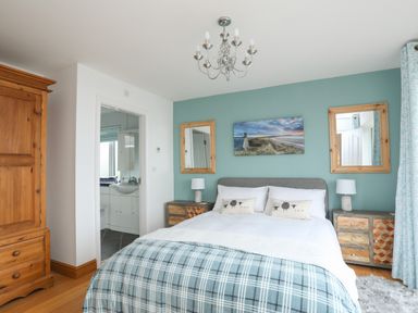 A bedroom with a bed two bedside tables lamps two mirrors a photograph and a wardrobe at Red Ridge in Llandanwg near Harlech