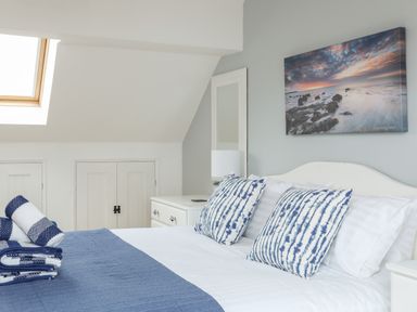 A bedroom with a bed having blue and white pillows and a blue throw at Red Ridge in Llandanwg near Harlech
