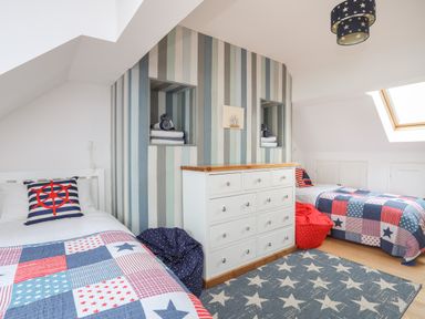 A bedroom with two single beds with patchwork quilts a white chest of drawers under a skylight window at Red Ridge in Llandanwg near Harlech