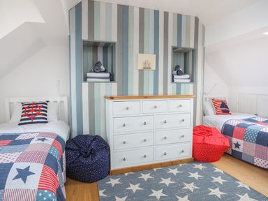 A bedroom with two single beds a dresser bean bags and striped accent wall at Red Ridge in Llandanwg near Harlech