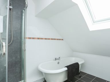 A bathroom with a bathtub a towel shower and a skylight at Red Ridge in Llandanwg near Harlech