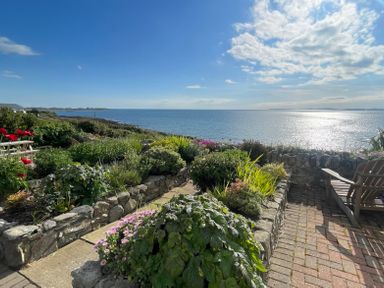 A garden with stone walls and plants overlooking the sea at Red Ridge in Llandanwg near Harlech