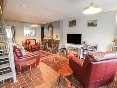A living room with red leather sofas a television and a fireplace at 3 Alma Terrace in Llanfairfechan
