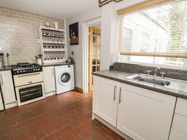 A kitchen with a stove oven washing machine dish rack and sink under a window at 3 Alma Terrace in Llanfairfechan