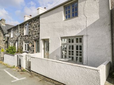 A row of stone and white painted houses with small fenced front patios and metal gates at 3 Alma Terrace in Llanfairfechan