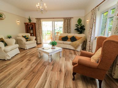 A living room with armchairs a sofa coffee table and wooden flooring at Downs View in Norton Ferris