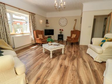 A living room with two orange armchairs a white coffee table and a television at Downs View in Norton Ferris