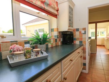 A kitchen countertop with jars flowers and a small TV near a window at Downs View in Norton Ferris