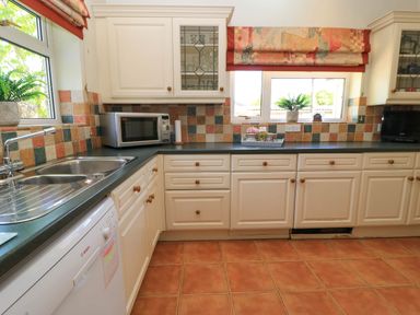 A kitchen with white cabinets green countertops a double sink microwave dishwasher and windows with patterned blinds at Downs View in Norton Ferris