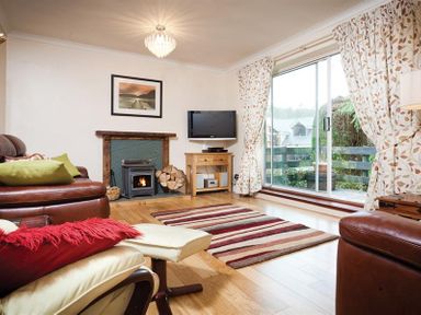 A living room with a fireplace a television a striped rug and sliding glass doors at Nutwood in Lakeside