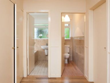 A hallway with two open doors showing a bathroom with a sink and a toilet at Nutwood in Lakeside