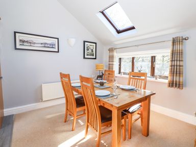 A dining room with a wooden table and four chairs under a skylight at Spring Cottage in Ambleside